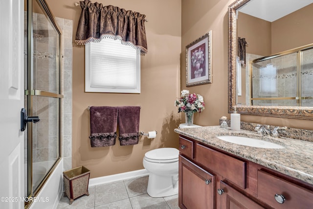 bathroom featuring toilet, enclosed tub / shower combo, vanity, tile patterned flooring, and baseboards