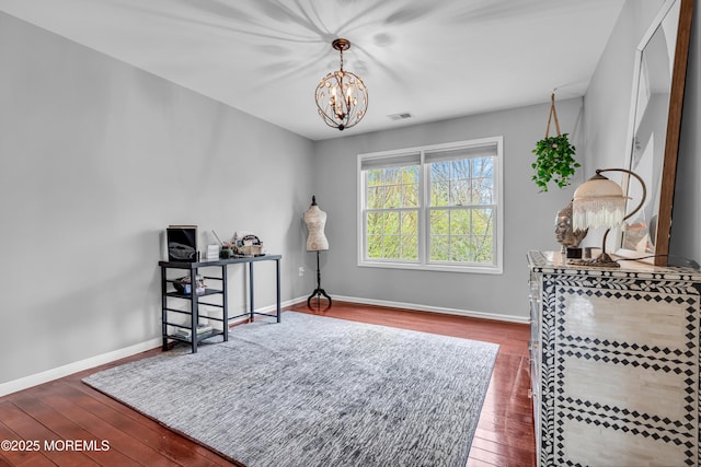 sitting room with hardwood / wood-style flooring, baseboards, visible vents, and an inviting chandelier