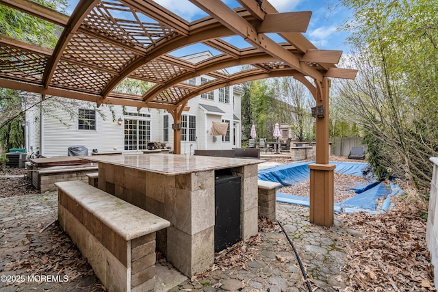 view of patio / terrace with a covered pool, fence, a pergola, and exterior kitchen