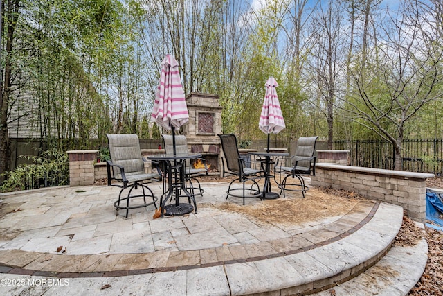 view of patio / terrace with an outdoor stone fireplace and a fenced backyard