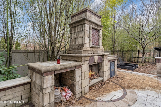 view of patio with a fenced backyard and an outdoor stone fireplace