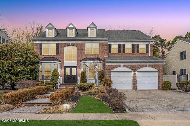 view of front of house with a garage, brick siding, and decorative driveway