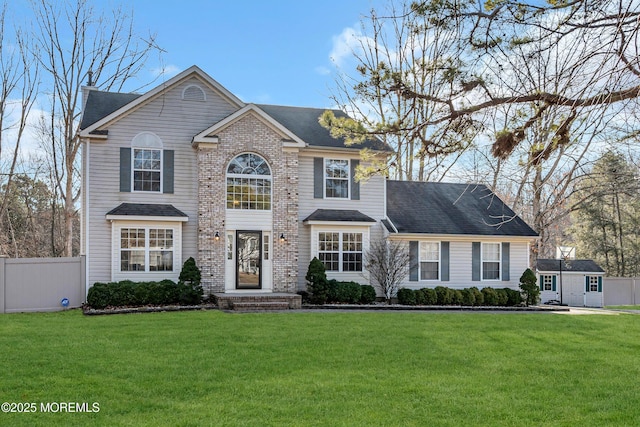 view of front of house featuring brick siding, a front yard, fence, and a shingled roof