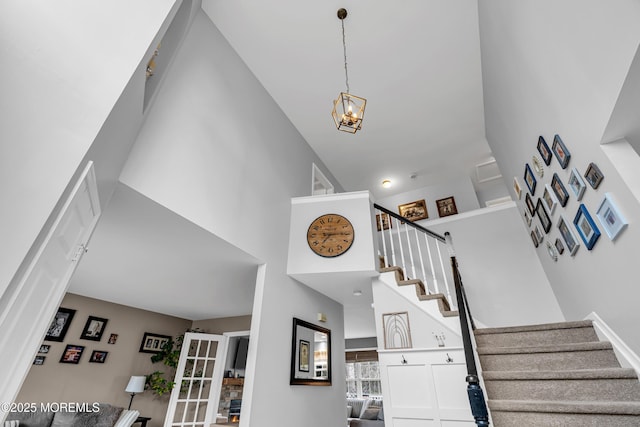 stairway with a high ceiling and a notable chandelier