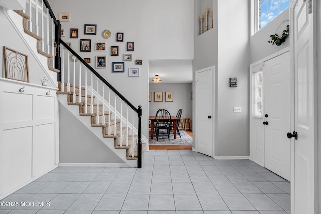 entrance foyer featuring a wealth of natural light, baseboards, stairway, and a high ceiling