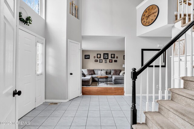 foyer with light tile patterned floors, a high ceiling, stairway, and plenty of natural light