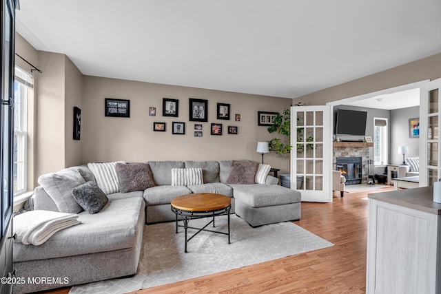 living area featuring a stone fireplace and light wood-style flooring