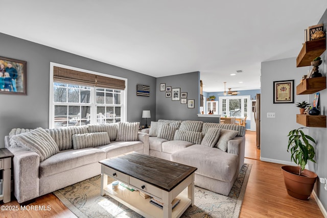 living room featuring a ceiling fan, light wood-style flooring, and baseboards