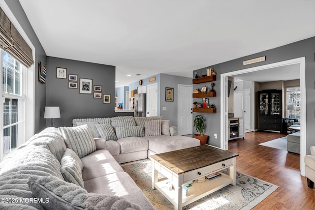 living area with a lit fireplace and wood finished floors