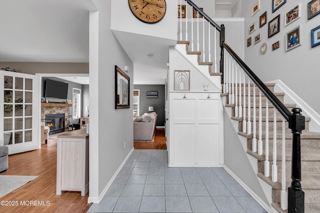 entryway featuring stairway, a fireplace, baseboards, and wood finished floors