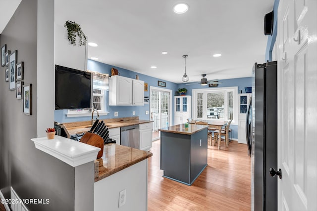 kitchen featuring a kitchen island, appliances with stainless steel finishes, a peninsula, stone counters, and white cabinetry