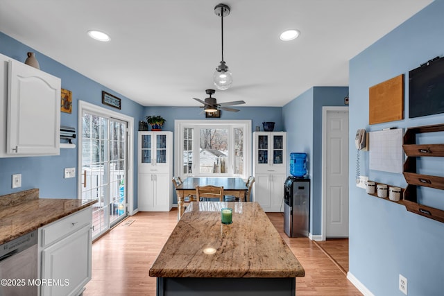 kitchen with light wood-style floors, white cabinets, stainless steel dishwasher, and light stone countertops