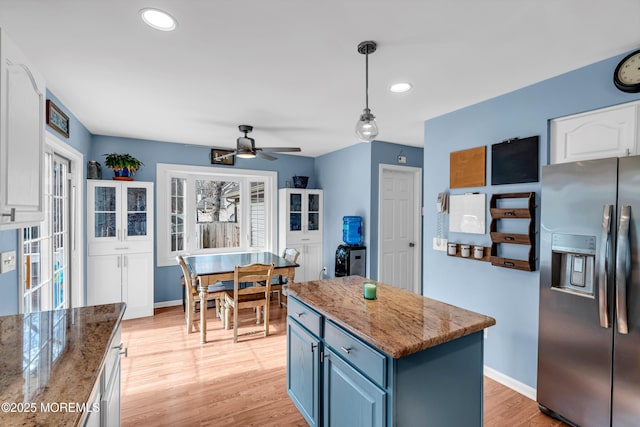 kitchen with stainless steel fridge, baseboards, blue cabinets, light wood-style floors, and white cabinetry