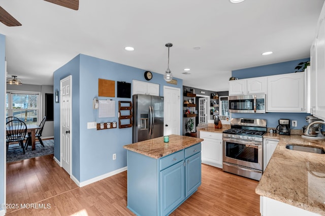 kitchen featuring light wood finished floors, white cabinetry, appliances with stainless steel finishes, and a sink