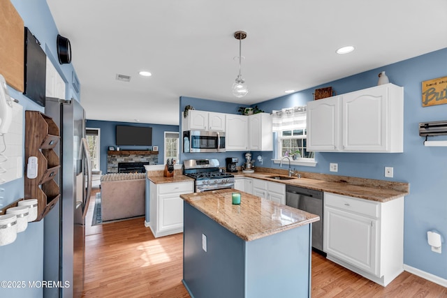 kitchen with stainless steel appliances, visible vents, a healthy amount of sunlight, a sink, and light stone countertops