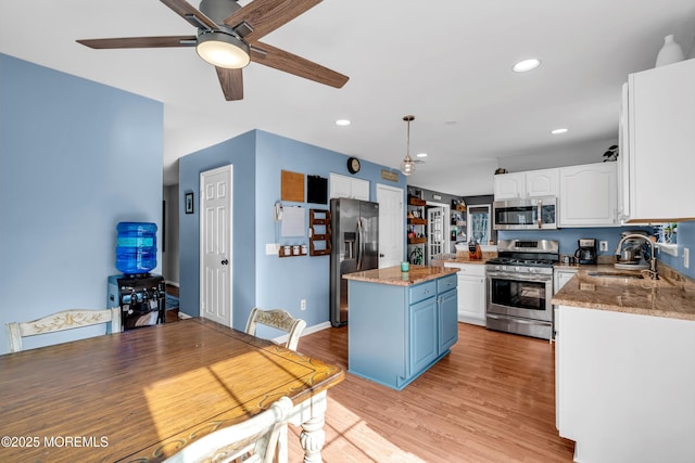 kitchen with stainless steel appliances, a center island, white cabinets, and a sink