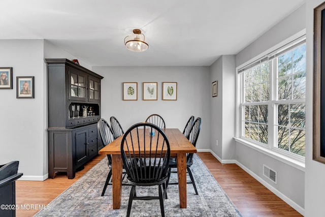 dining area featuring light wood-style floors, visible vents, and baseboards