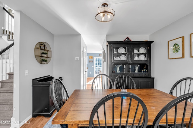 dining space with stairs, wood finished floors, and baseboards