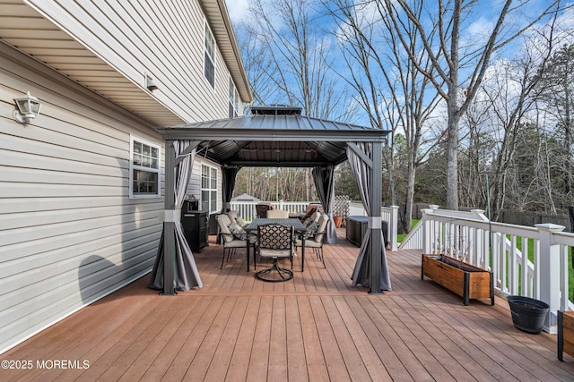 deck with outdoor dining area, fence, and a gazebo