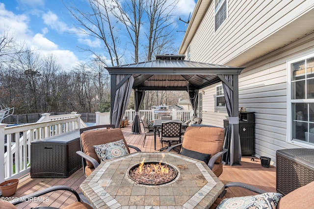 wooden terrace with a fire pit, a gazebo, outdoor dining area, and fence