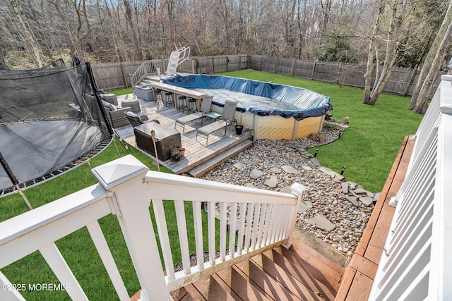 exterior space with a lawn, a fenced in pool, a fenced backyard, grilling area, and a trampoline