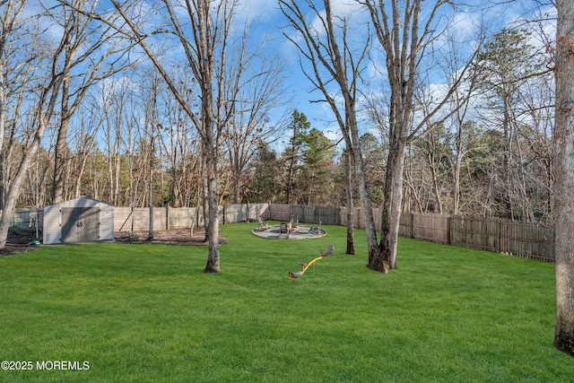 view of yard with a storage unit, an outdoor fire pit, an outdoor structure, and a fenced backyard