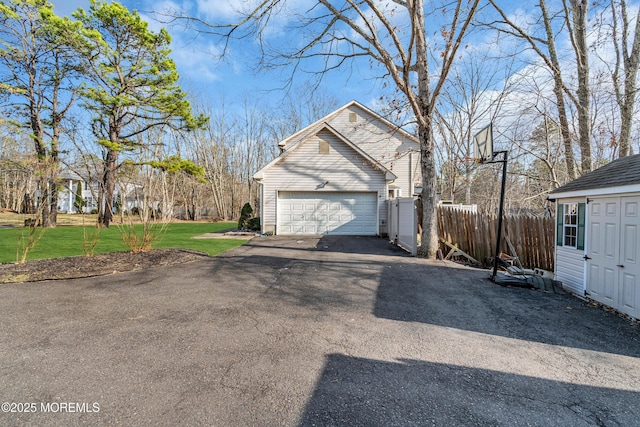 view of side of property with a garage, fence, a lawn, and an outdoor structure