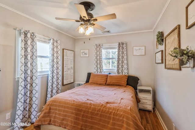 bedroom featuring baseboards, wood finished floors, visible vents, and crown molding