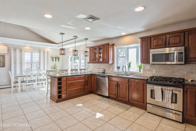 kitchen with a peninsula, a sink, visible vents, appliances with stainless steel finishes, and dark countertops