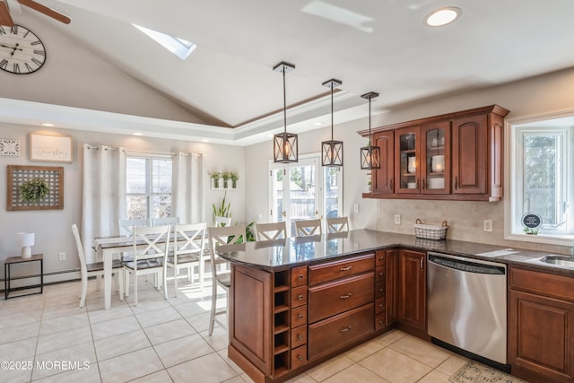 kitchen featuring lofted ceiling with skylight, glass insert cabinets, a peninsula, stainless steel dishwasher, and backsplash