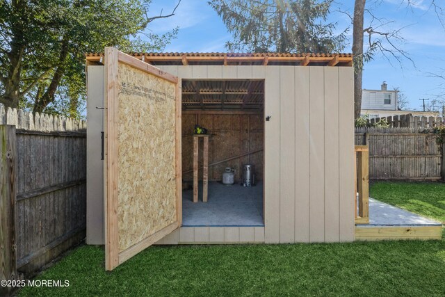 view of outdoor structure with a fenced backyard and an outbuilding