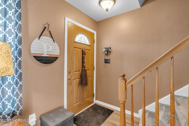 entryway featuring stairway, wood finished floors, and baseboards