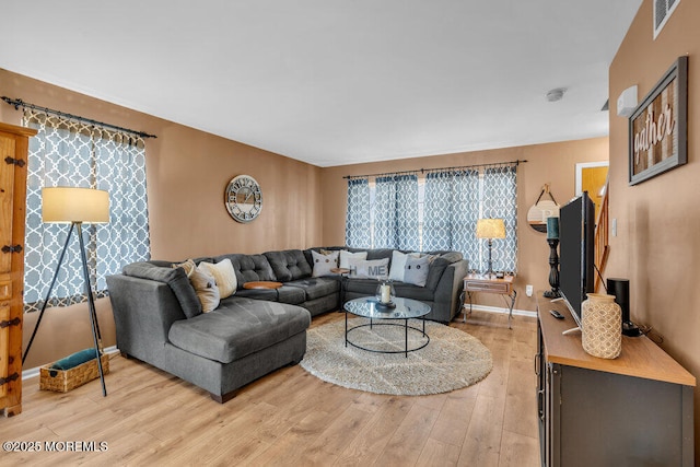 living room featuring light wood-type flooring, visible vents, and baseboards