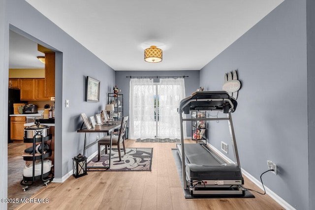 workout area with baseboards, visible vents, and light wood-style floors