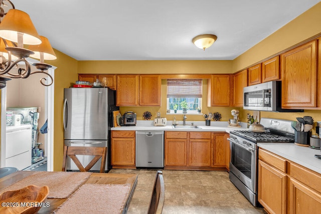 kitchen featuring washer / clothes dryer, stainless steel appliances, light countertops, a chandelier, and a sink