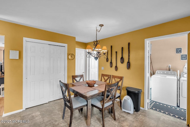 dining space featuring a chandelier, baseboards, and washer and dryer