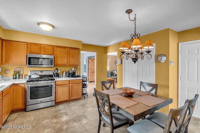 kitchen with stainless steel appliances, brown cabinetry, light countertops, and decorative light fixtures