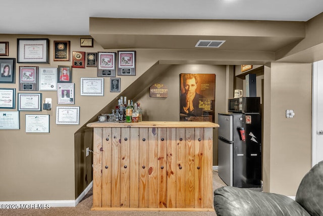 bar with black microwave, carpet flooring, visible vents, baseboards, and freestanding refrigerator