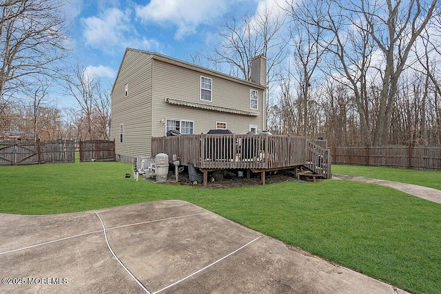 back of property with a fenced backyard, a lawn, a chimney, and a wooden deck