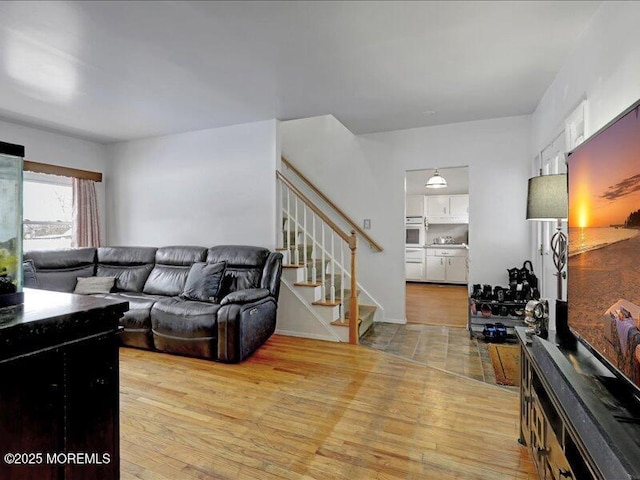 living area with light wood finished floors and stairway