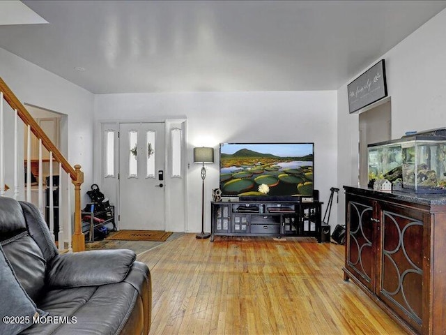 living area featuring stairs and light wood-style flooring