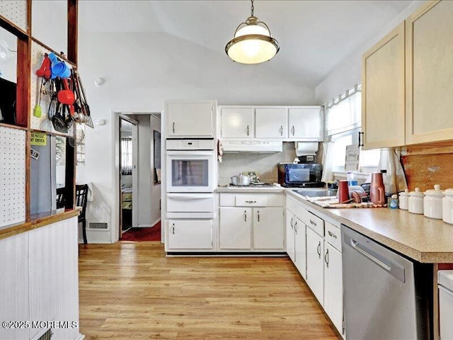 kitchen featuring black microwave, vaulted ceiling, light countertops, white oven, and dishwasher