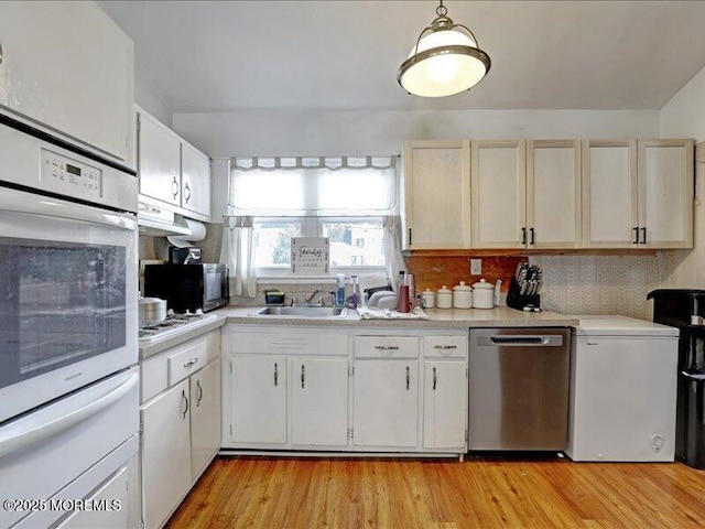 kitchen with light countertops, oven, a sink, and stainless steel dishwasher