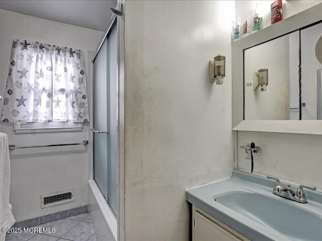 full bath featuring a shower with shower door, visible vents, vanity, and tile patterned floors