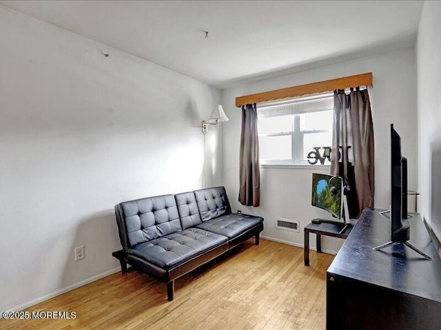 living area with light wood-style floors, visible vents, and baseboards