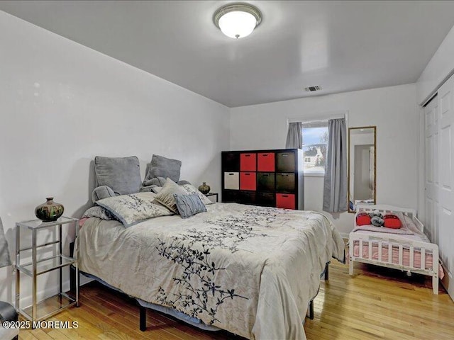 bedroom with a closet, visible vents, and wood finished floors