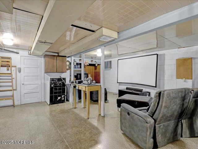 home theater room featuring concrete block wall and speckled floor