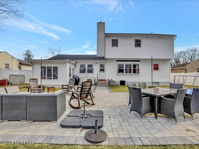 back of house featuring entry steps, fence, an outdoor living space, a chimney, and a patio area