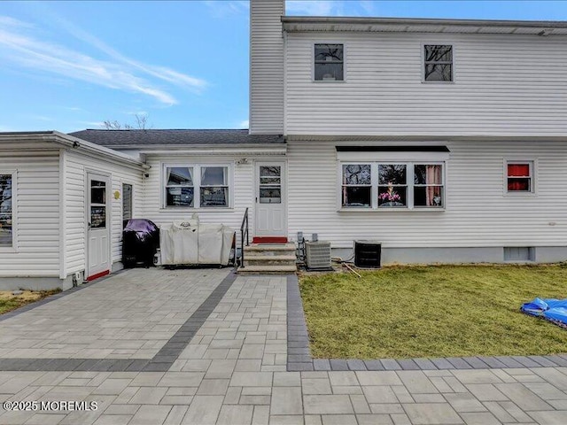 rear view of property with entry steps, a yard, a chimney, and central air condition unit