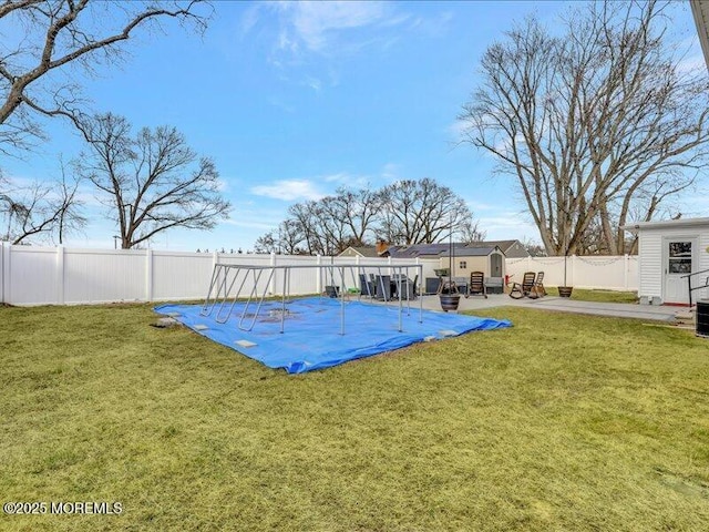 view of swimming pool featuring an outbuilding, a yard, a patio area, and a fenced backyard